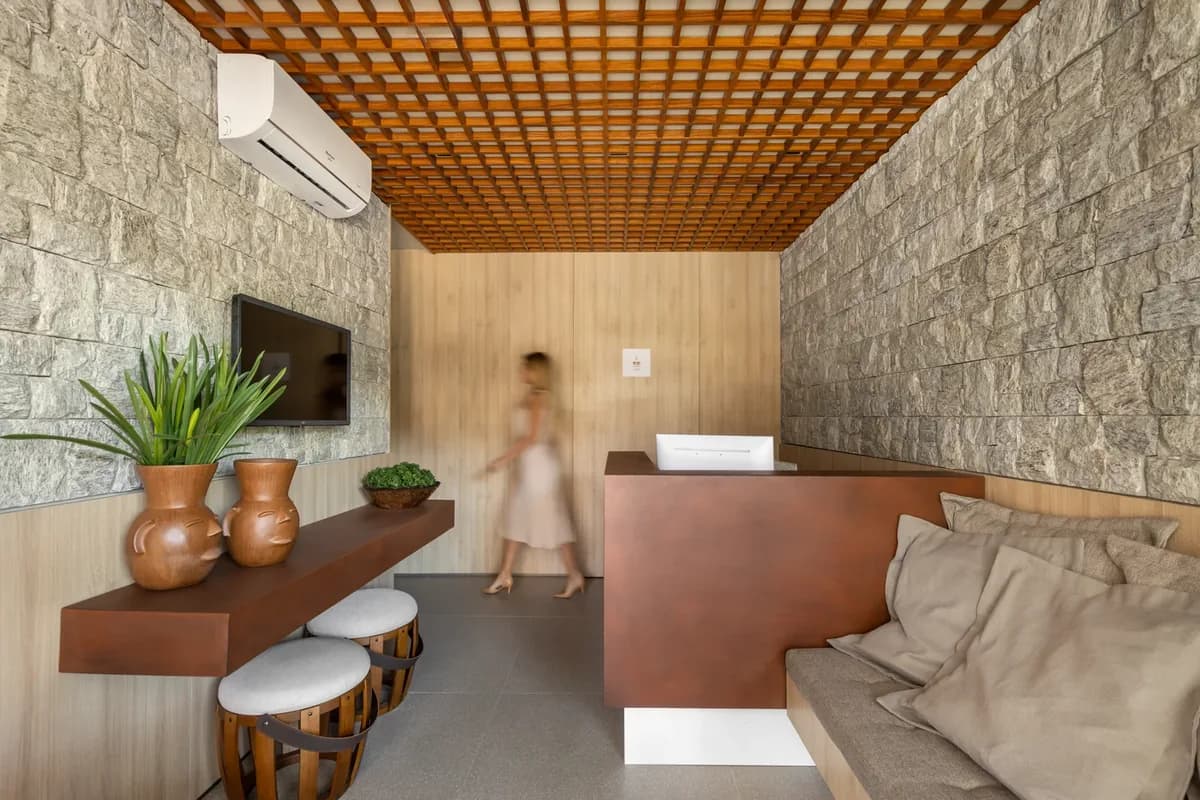 Recepção da unidade 2 da Bella Vita, com balcão em aço corten e teto de madeira